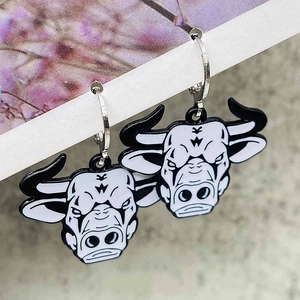 Detailed shot of retro punk style black bull head earrings on display card