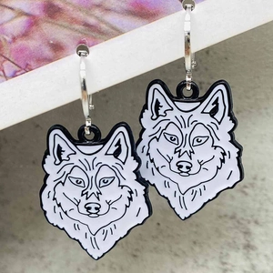 Vintage black and white wolf head earrings with silver hoop on magazine edge