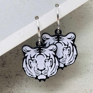 Close-up of black and white tiger head earrings with polished silver hoop dangles