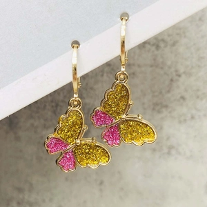 Close-up of golden hoop earrings featuring colorful glitter butterfly charms