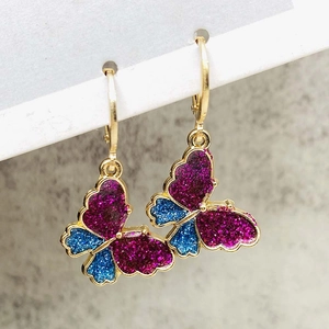 Sparkly butterfly drop earrings with purple and blue glitter on gold metal ear hoops