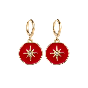 Detailed shot of golden hoop earrings featuring red enamel charms with star motifs