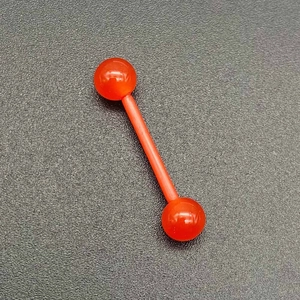 Gros plan sur un bijou de piercing barbell en acrylique orange translucide pour langue