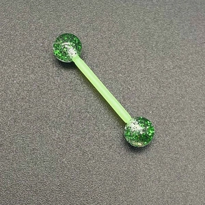 Détail macro du piercing en acrylique vert pailleté avec tige flexible en bioflex