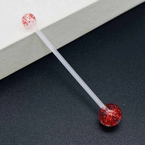 Macro detail of acrylic belly button ring with sparkling red glitter ball ends