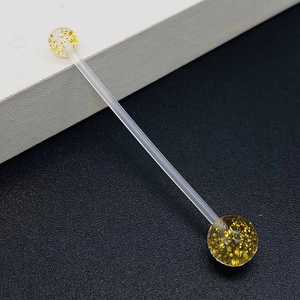Macro shot of flexible industrial barbell featuring gold glitter acrylic beads detailing