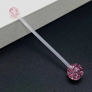 Macro detail of flexible acrylic belly bar with sparkling pink glitter ball ends