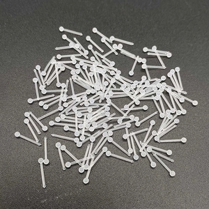 Macro shot of clear acrylic nose studs and ear retainers on black textured surface