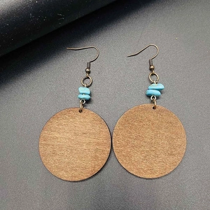 Vintage round wooden earrings with turquoise beads and bronze hooks on black texture