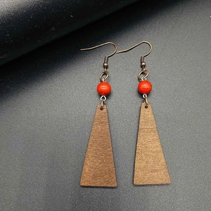 Bohemian vintage wood earrings with bronze hooks and red beads on a black surface