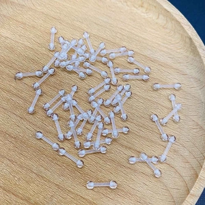 Barras retenedoras transparentes de acrílico para piercings sobre bandeja de madera