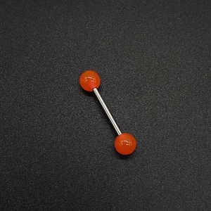 Gros plan d'un piercing barbell en acrylique orange avec barre en acier inoxydable