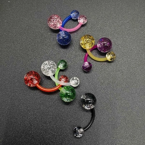 Macro view of colorful glitter acrylic navel rings with curved bars on black texture