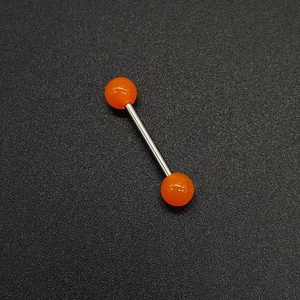 Détail d'un piercing en acier inoxydable avec boules acryliques orange sur fond noir