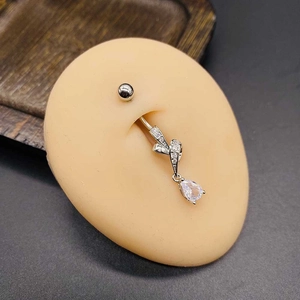 Macro detail of silver navel ring with crystal bow and pear-shaped zircon drop