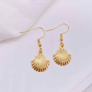 Close-up of gold seashell drop earrings with detailed textures on white background
