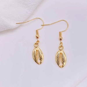 Close-up of gold conch shell drop earrings with metallic texture and sleek hooks