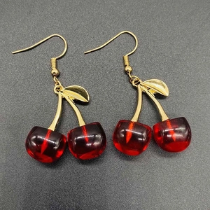 Elegant cherry drop earrings with red resin fruit and golden leaves on grey background
