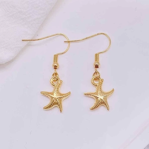 Detailed view of golden starfish drop earrings with textured surface and fishhook design