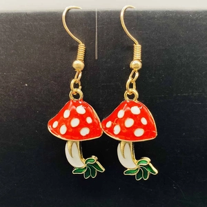 Détail de boucles d'oreilles champignons rouges à pois blancs et feuilles vertes