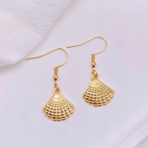 Close-up of golden shell earrings with detailed radial stripes and french hooks
