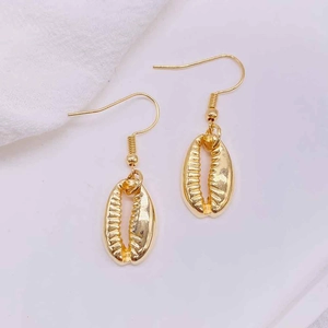 Detail of golden shell-shaped drop earrings with a bright metallic luster for women