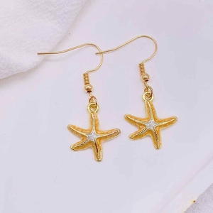 Detailed macro view of golden starfish earrings with vibrant orange enamel coating