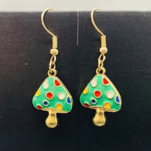 Vue rapprochée de boucles d'oreilles champignons verts à pois et crochets dorés
