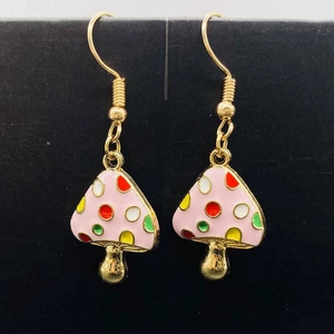 Détail de boucles d'oreilles champignons en émail rose avec des points colorés
