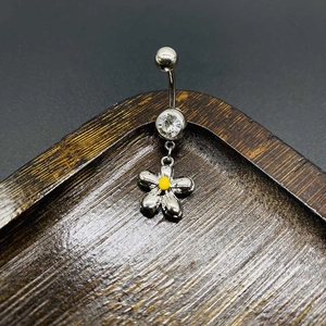 Detail view of silver stainless steel navel ring with flower pendant and clear zircon