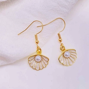 Detailed macro shot of a seashell dangle earring with white enamel and a center pearl