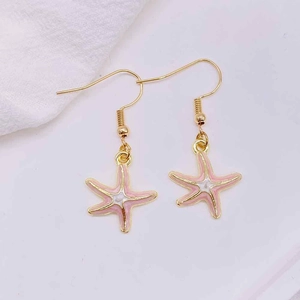 Close-up of golden starfish earrings with pink and white enamel on a soft background