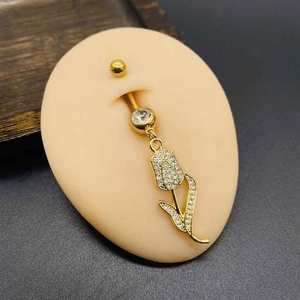 Detailed close-up of golden tulip belly ring with white crystals on a silicone model