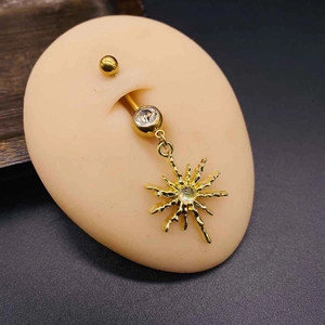 Detailed view of gold belly button ring with sunburst pendant and crystal on mannequin
