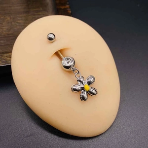 Close-up of silver daisy navel piercing with yellow flower center and clear crystals