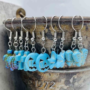 Détail de boucles d'oreilles turquoise argentées avec breloques tortue, citrouille et papillon