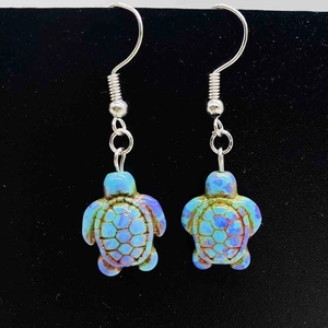 Détail des boucles d'oreilles tortue avec motifs turquoise et crochets en argent