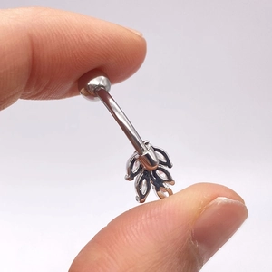 Primer plano de piercing de ombligo de hoja con circonitas brillantes en acero plateado