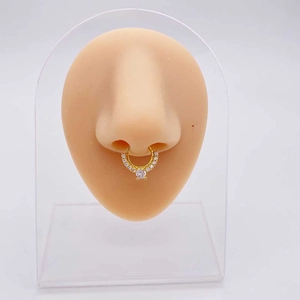 Detail van een gouden zirkoon septumring getoond op een siliconen neusmodel voor piercings