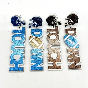 Détail de boucles d'oreilles casque football avec pendentif TOUCH DOWN pailleté en bleu et marron