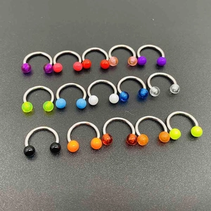 Set of 12 colorful horseshoe piercing rings with metal barbells on a textured background