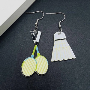 Vue macro des boucles d'oreilles asymétriques avec raquette et volant de badminton