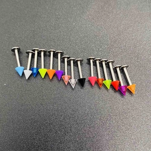 Macro shot of 16 colorful acrylic cone labret studs set on a textured grey surface