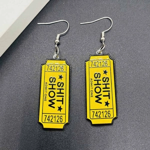 Détail des boucles d'oreilles ticket jaune en acrylique avec gravure SHIT SHOW unique