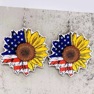 Detail of wooden sunflower earrings with American flag pattern on a stone surface