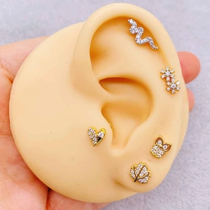 Macro view of stainless steel labret studs with cross flower and snake zircon designs
