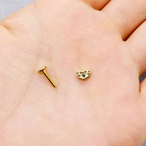 Golden stainless steel piercing jewelry with crescent shape and zircon crystals in hand
