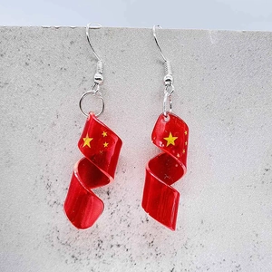 Detalle de los pendientes espirales de acrílico rojo con estrellas amarillas y diseño patrio