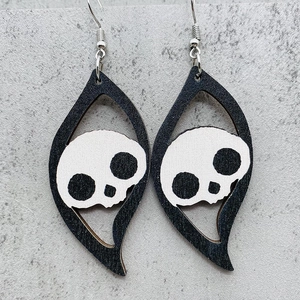 Detail of gothic wooden Halloween earrings featuring white skull inserts and black frames