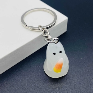 Macro detail of a 3D resin ghost keychain holding candy corn with silver metal ring
